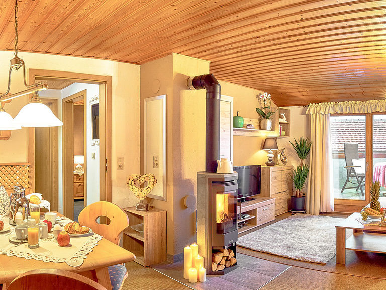 Gemütliches Wohnzimmer mit Kaminofen und bayerischer Eckbank in der Ferienwohnung in Bodenmais